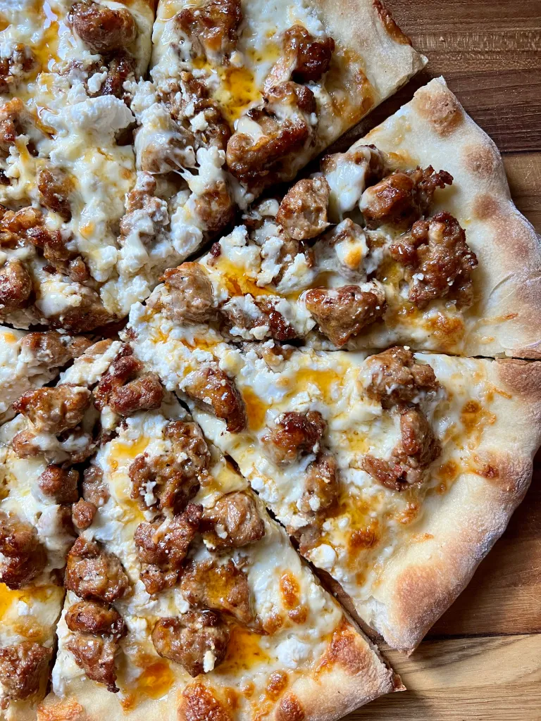 Perfectly baked handcrafted pizza with Italian flavored pork sausage, goat cheese, and olive oil