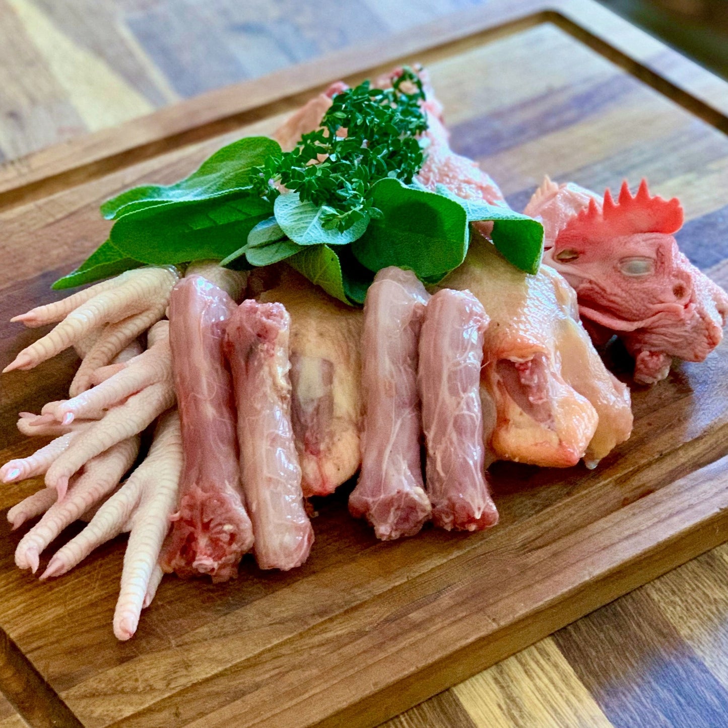 Organic pasture raised chicken necks, backbones, feet, and heads with herbs on cutting board for making nutrient dense healing bone broth.