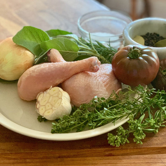 Organic pasture raised chicken leg quarters including the drum and thigh connected with herbs and fresh vegetables great for grilling, baking, or instapot stew.